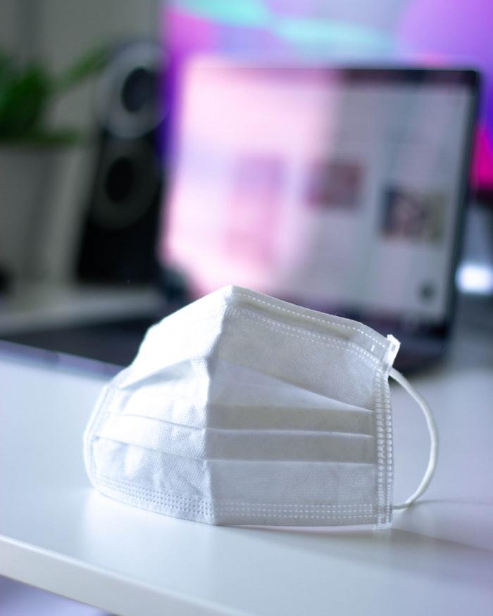 Photograph of a mask with a computer in the background.